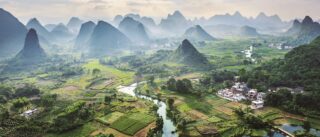 Lotnicza panorama doliny krasowej z polami ryżowymi i wioską w regionie Guilin – wyprawa rowerowa Chiny