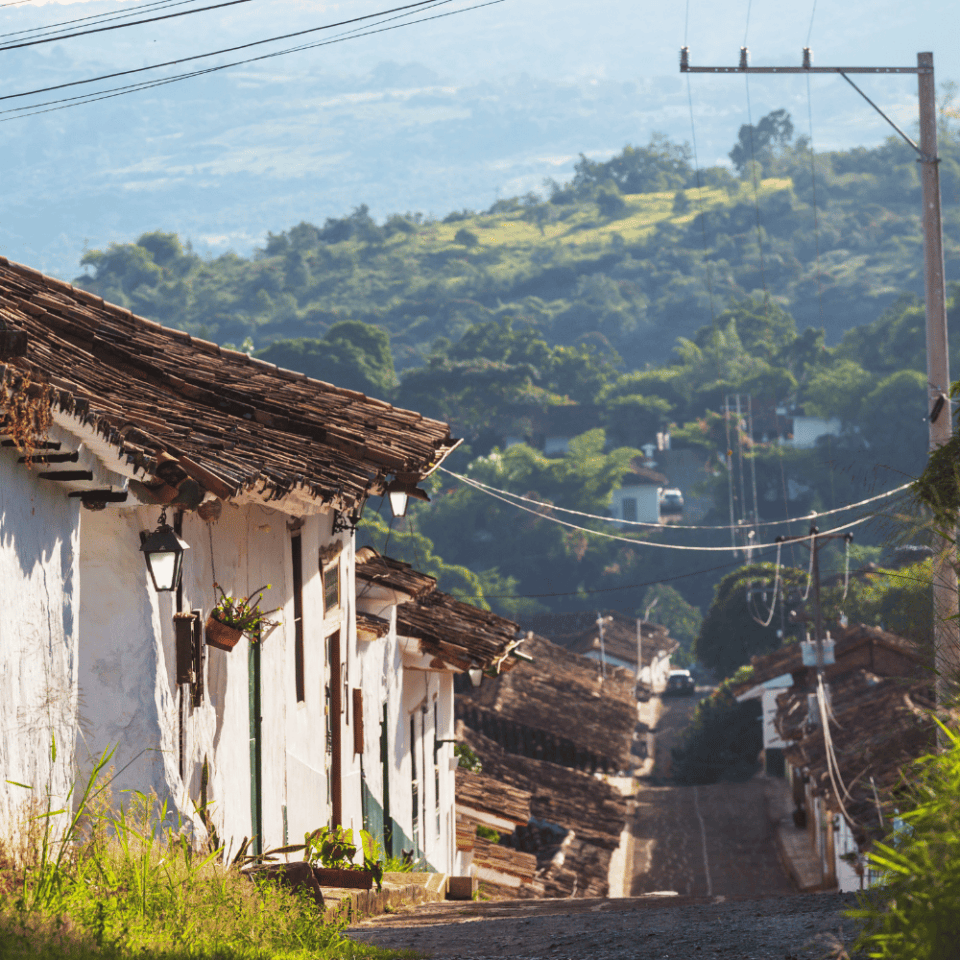 Stroma, brukowana ulica Barichary z tradycyjnymi białymi domami, kwiatami i latarniami w porannej poświacie.