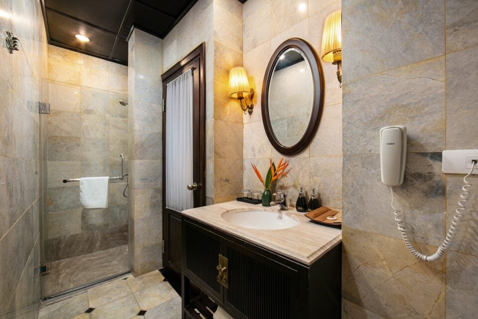 Łazienka w hotelowym pokoju deluxe w Hanoi &ndash; prysznic, duże lustro i eleganckie wykończenia.