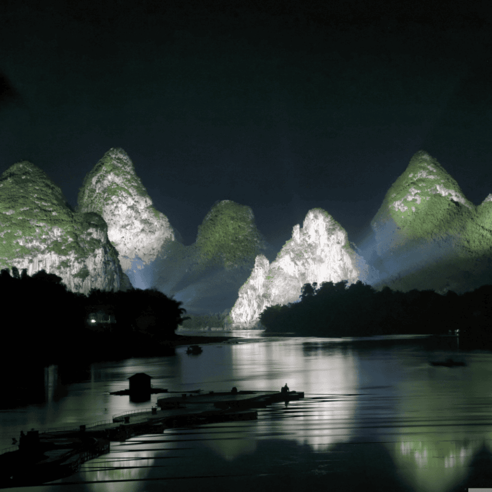 Oświetlone reflektorami góry krasowe odbijające się nocą w wodach rzeki Li w Yangshuo.