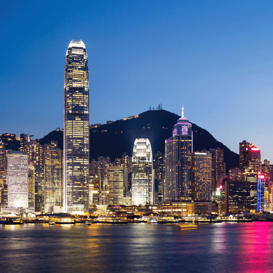 Rozświetlone wieżowce Hongkongu nocą z odbiciem świateł w wodach zatoki.