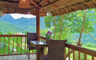 Taras bambusowej chatki z widokiem na góry i tropikalną zieleń w okolicy Pu Luong w Wietnamie.