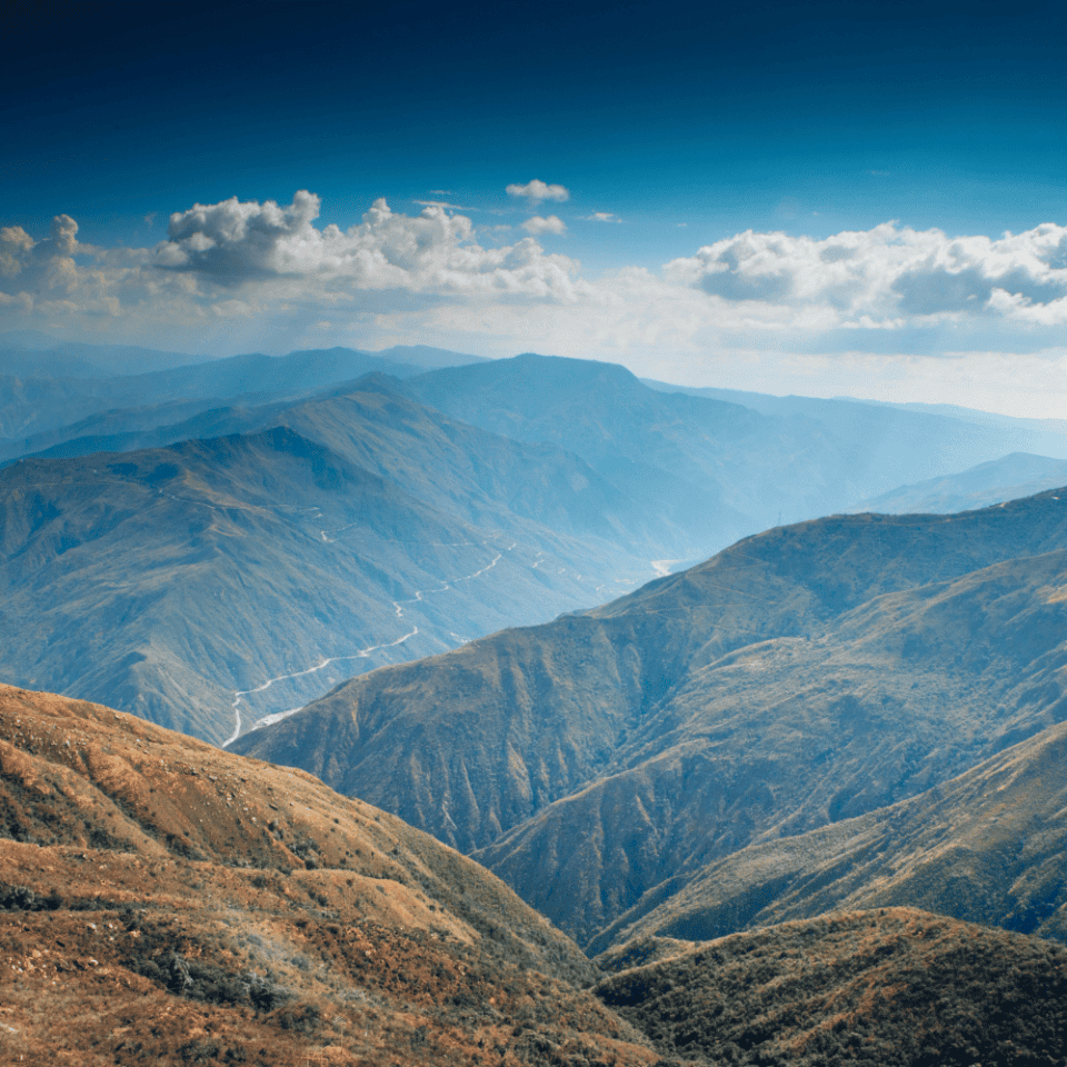 Szeroka panorama na głębokie doliny i pasma górskie Chicamocha przy intensywnie błękitnym niebie.