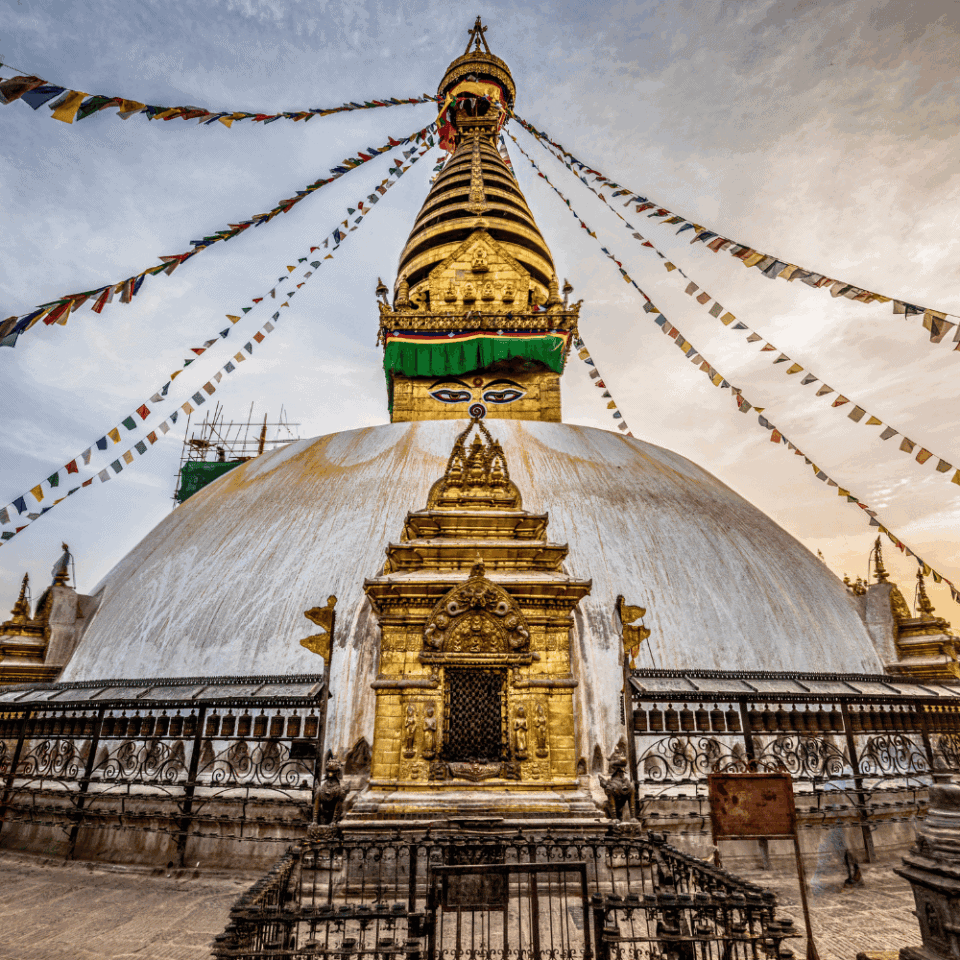 Monumentalna Złota Stupa Swayambhunath (Małpia Świątynia) w Katmandu, Nepal, ozdobiona kolorowymi flagami modlitewnymi. Stupa charakteryzuje się dużymi oczami Buddy malowanymi na jej szczycie.