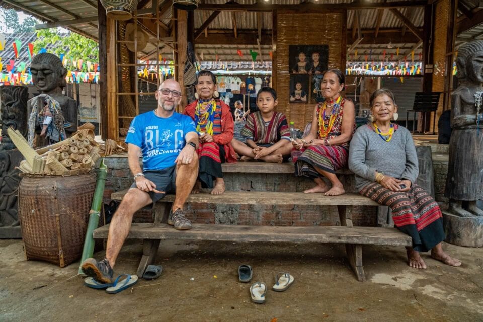 Spotkanie z lokalną społecznością w Laosie – uczestnicy wyprawy siedzą z mieszkańcami w tradycyjnym drewnianym domu.