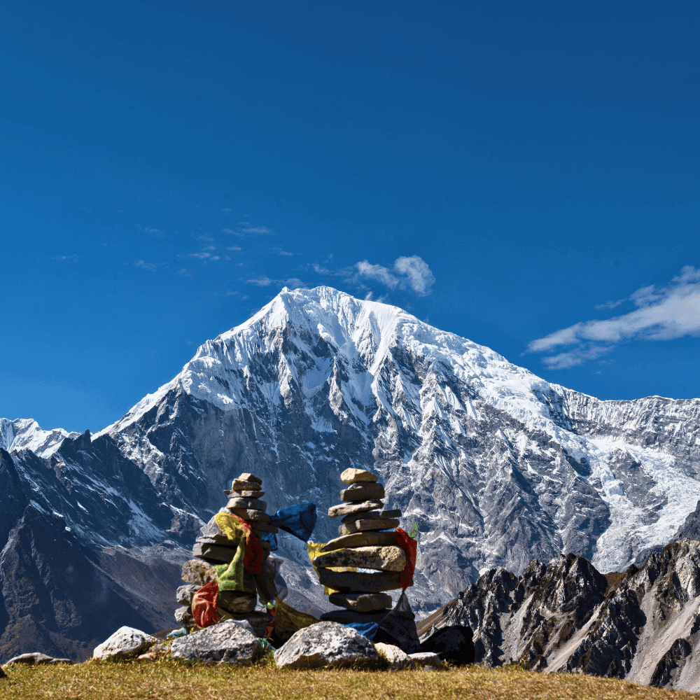 Stos kamieni (chorten) z buddyjskimi flagami modlitewnymi na tle majestatycznego, ośnieżonego szczytu Langtang Lirung w Dolinie Langtang w Nepalu.