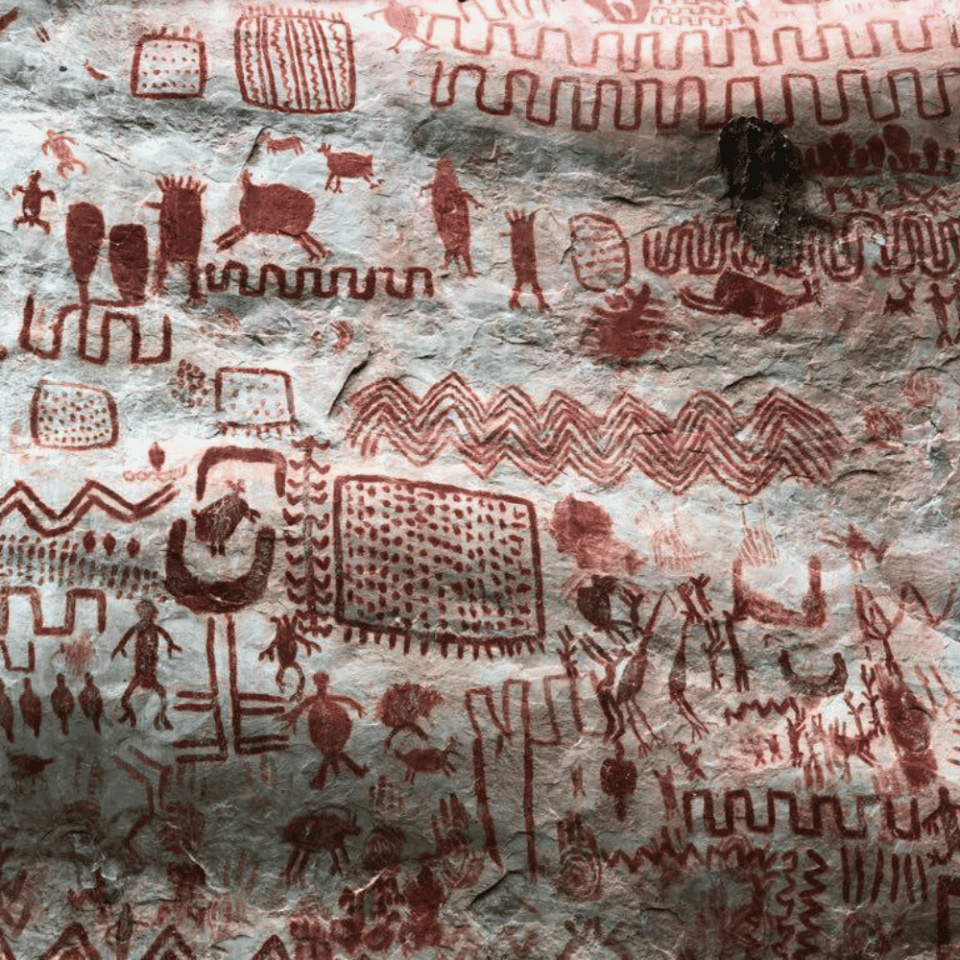 Zespół prekolumbijskich malowideł naskalnych w Serranía de La Lindosa – złożone symbole, ludzkie postacie i zwierzęta w czerwonym pigmentach na skalnej ścianie.
