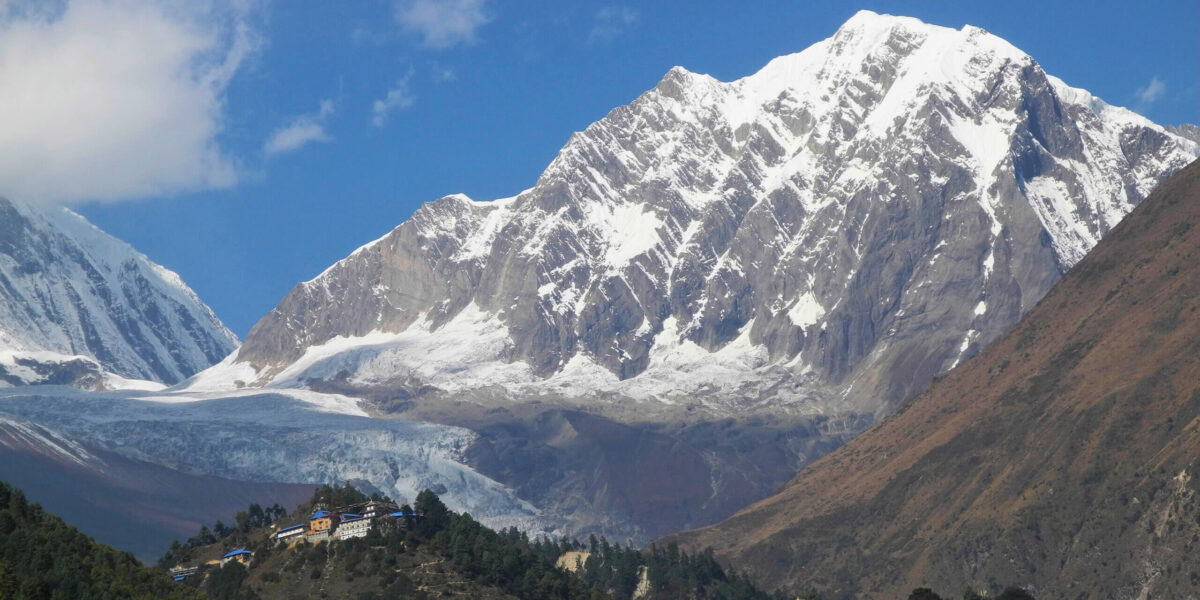 Himalajska wioska z klasztorem u podnóża Manaslu w Nepalu, z lodowcem i majestatycznymi szczytami w tle