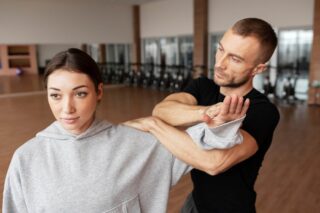 Instruktor pokazuje kobiecie technikę samoobrony – praktyczne szkolenie z samoobrony dla kobiet