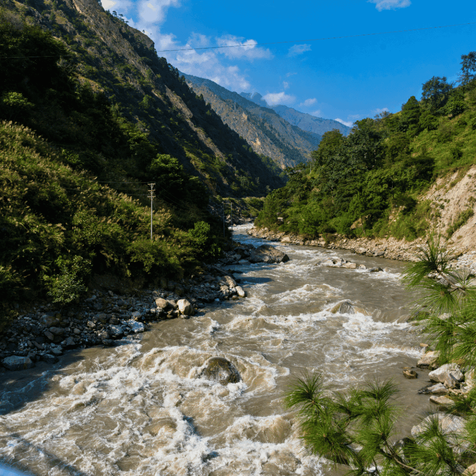 Wartka rzeka Trishuli płynąca przez zieloną dolinę otoczoną wysokimi, zalesionymi górami. Zdjęcie wykonane w okolicach Syabrubesi, Nepal.