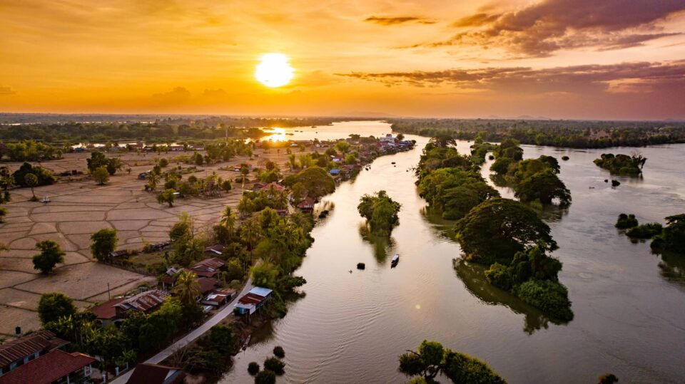 Zachód słońca nad Si Phan Don – archipelagiem Czterech Tysięcy Wysp na Mekongu w południowym Laosie, ukazującym rozproszone wyspy, rzekę i złote niebo.