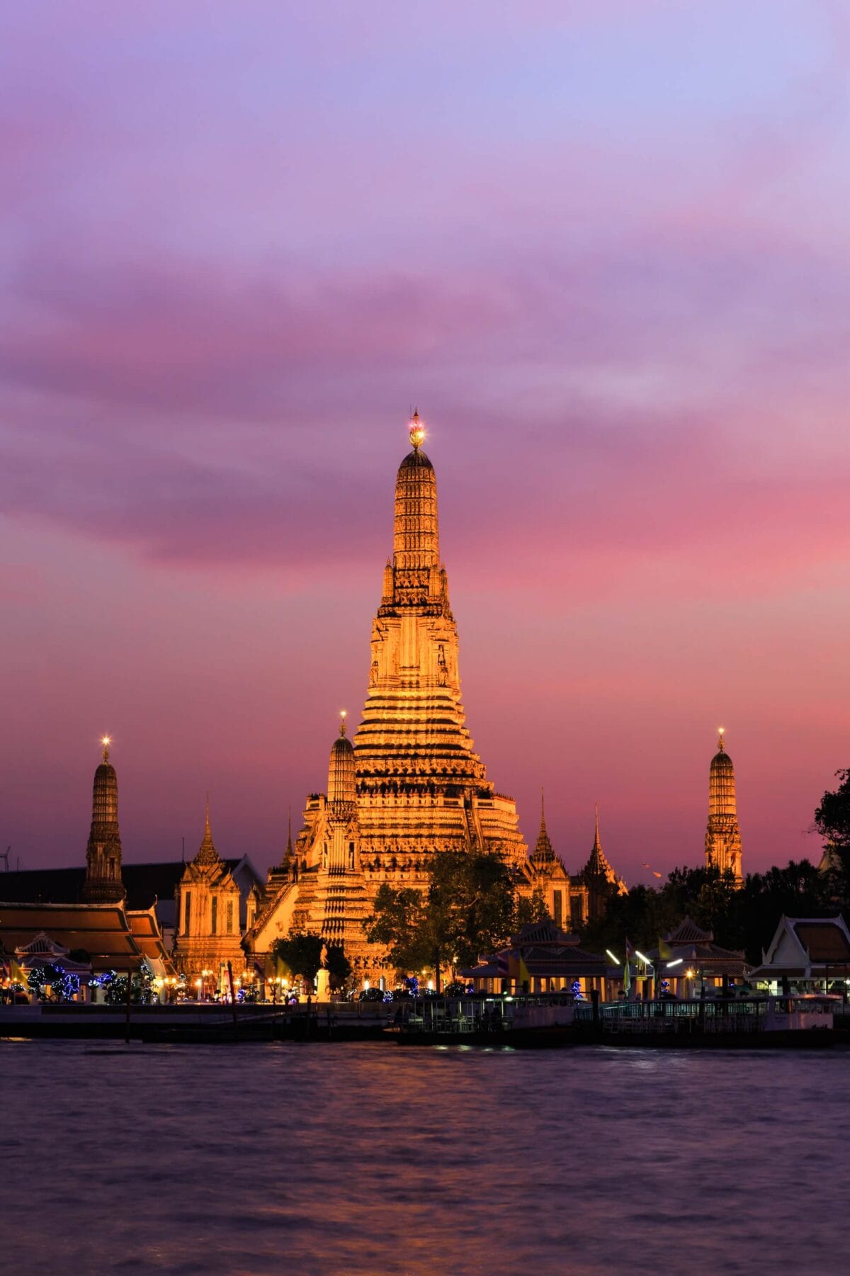 Świątynia Wat Arun o zmierzchu nad rzeką Chao Phraya w Bangkoku w Tajlandii, w różowym świetle nieba.