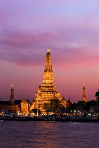 Świątynia Wat Arun o zmierzchu nad rzeką Chao Phraya w Bangkoku w Tajlandii, w różowym świetle nieba.