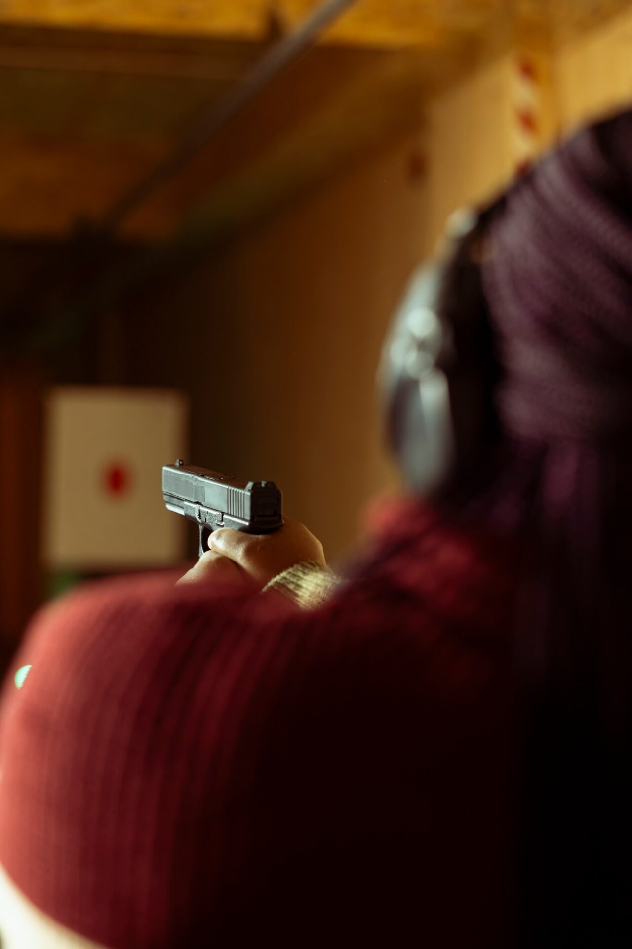 Kobieta strzela z pistoletu na strzelnicy w słuchawkach ochronnych – praktyczne zajęcia strzeleckie