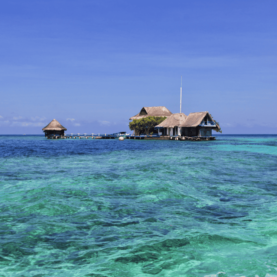 Zielone wyspy otoczone rafą koralową i lazurową wodą w Archipelagu Różańcowym, uchwycone z powietrza z motorówką na wodzie.