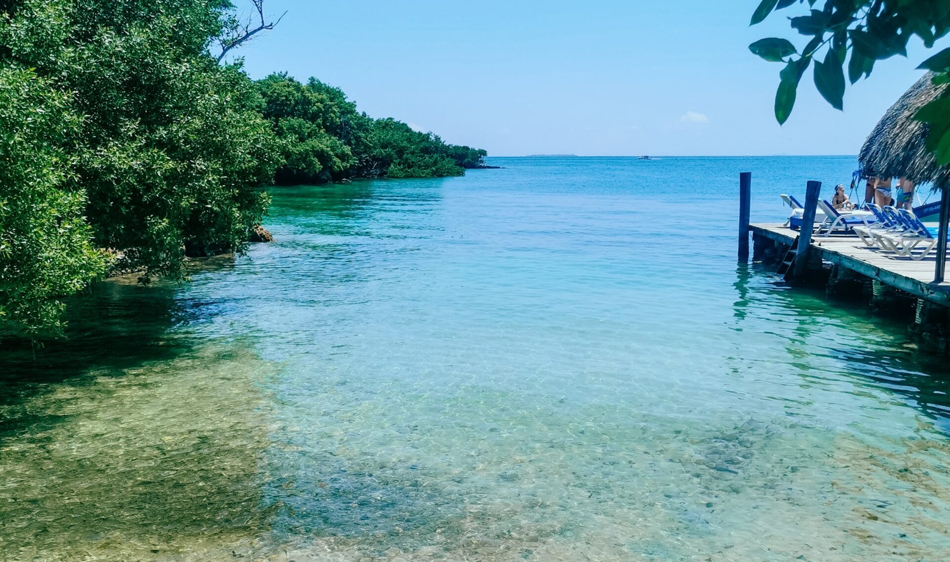 Krystalicznie czysta woda, tropikalna roślinność i drewniany pomost z leżakami na Wyspach Różańcowych.